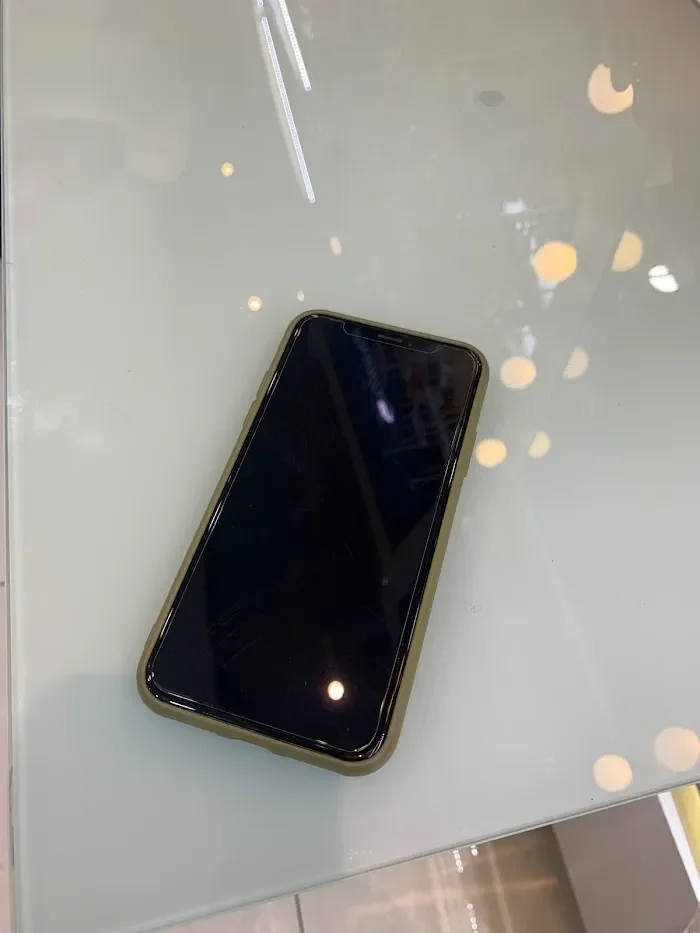 Smartphone with black screen resting on glass table